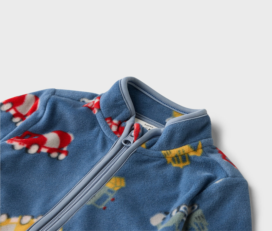 Zbliżenie na niebieską bluzę polarową zapinaną na zamek z kolorowymi motywami pojazdów.