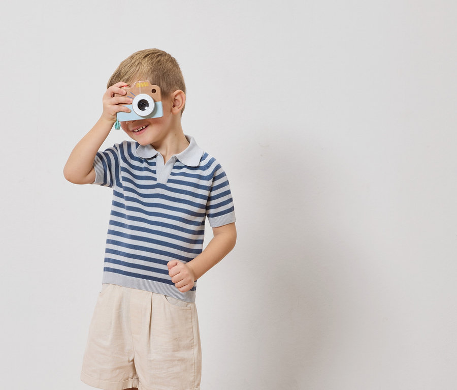 Chłopiec trzyma zabawkę aparatu przed okiem.