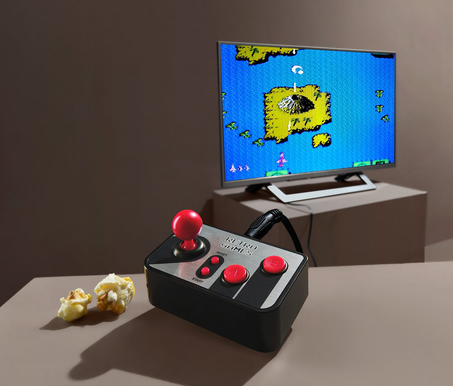 Konsola retro do gier telewizyjnych z joystickiem i popcornem. W tle telewizor wyświetla grę.