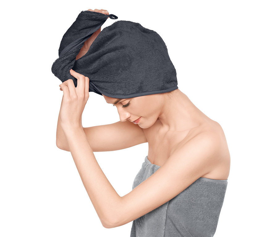 Kobieta zakłada szary turban do włosów.