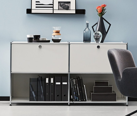 Pokój z antracytowym krzesłem biurowym i metalowymi szafkami typu sideboard. Jedna antracytowa i dwie białe metalowe szafki typu sideboard CN3 z 2 klapami do indywidualnego rozmieszczenia.