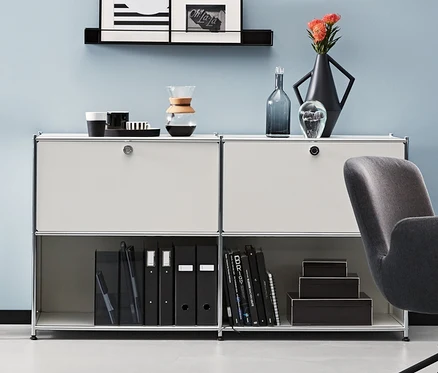 Pokój z antracytowym krzesłem biurowym i metalowymi szafkami typu sideboard. Jedna antracytowa i dwie białe metalowe szafki typu sideboard CN3 z 2 klapami do indywidualnego rozmieszczenia.
