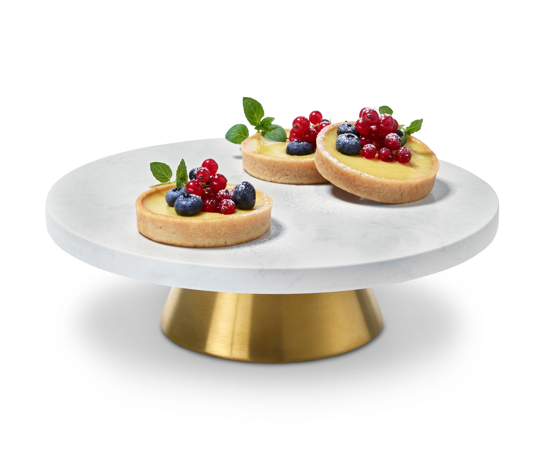 Trzy tartaletki z owocami na paterze na ciasto i talerzu do serwowania.