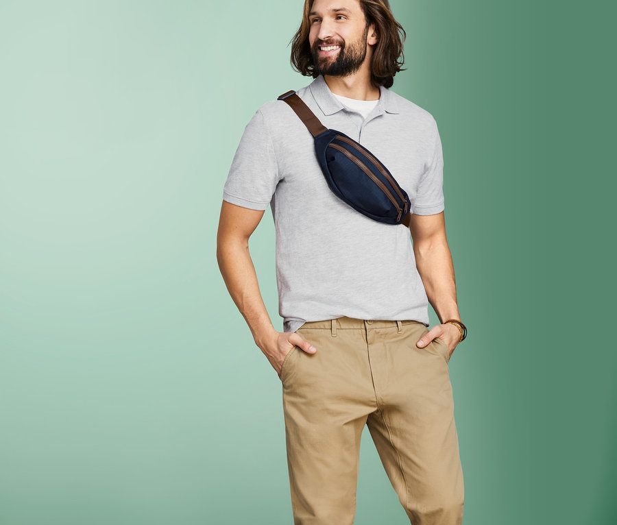 Mężczyzna z saszetką biodrową na piersi stoi na tle zielonego tła.