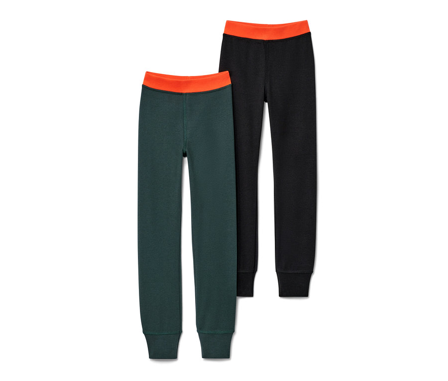 Dwie pary zimowych kalesonów dziecięcych: jedna para ciemnozielona, druga czarna, obie z pomarańczowym pasem.