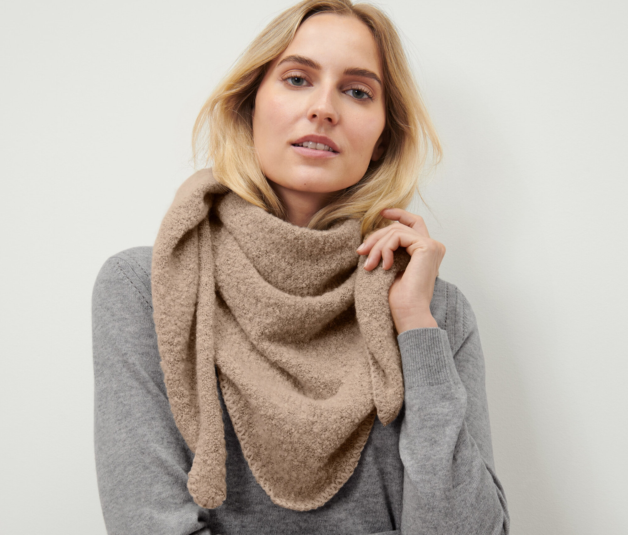 Blondynka nosi trójkątny szal z imitacji przędzy bouclé.