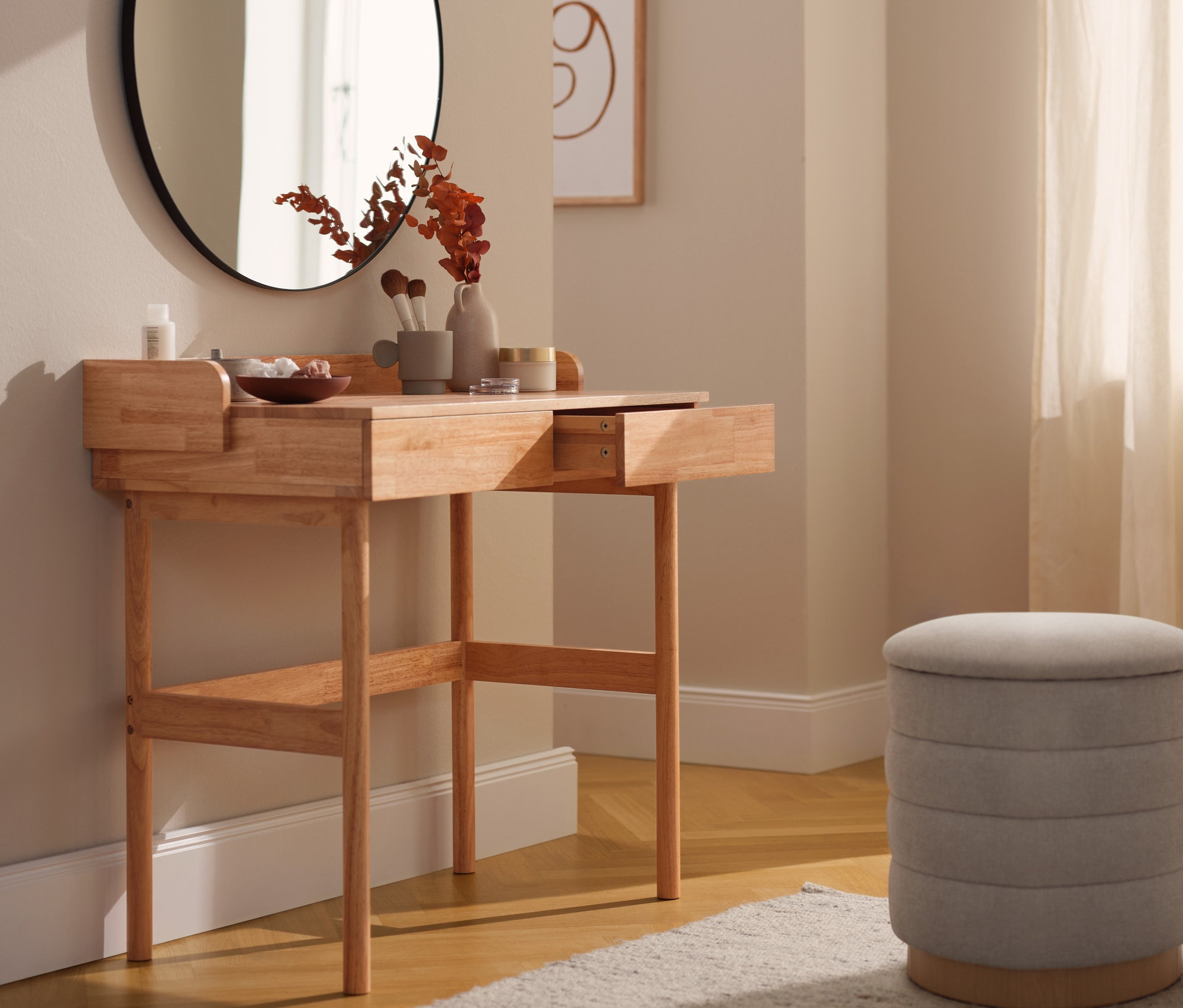 Toaletka z szufladami, okrągłe lustro i beżowy stołek w pokoju.
