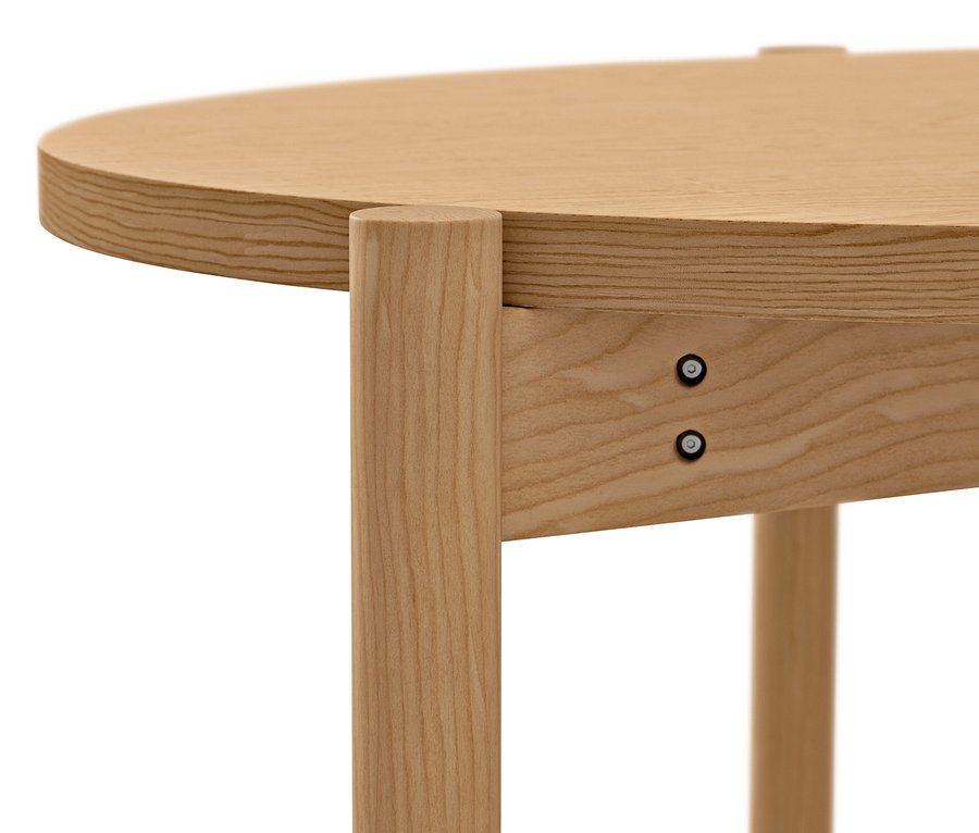 Detal okrągłego stolika kawowego z jasnego drewna z widocznymi śrubami.