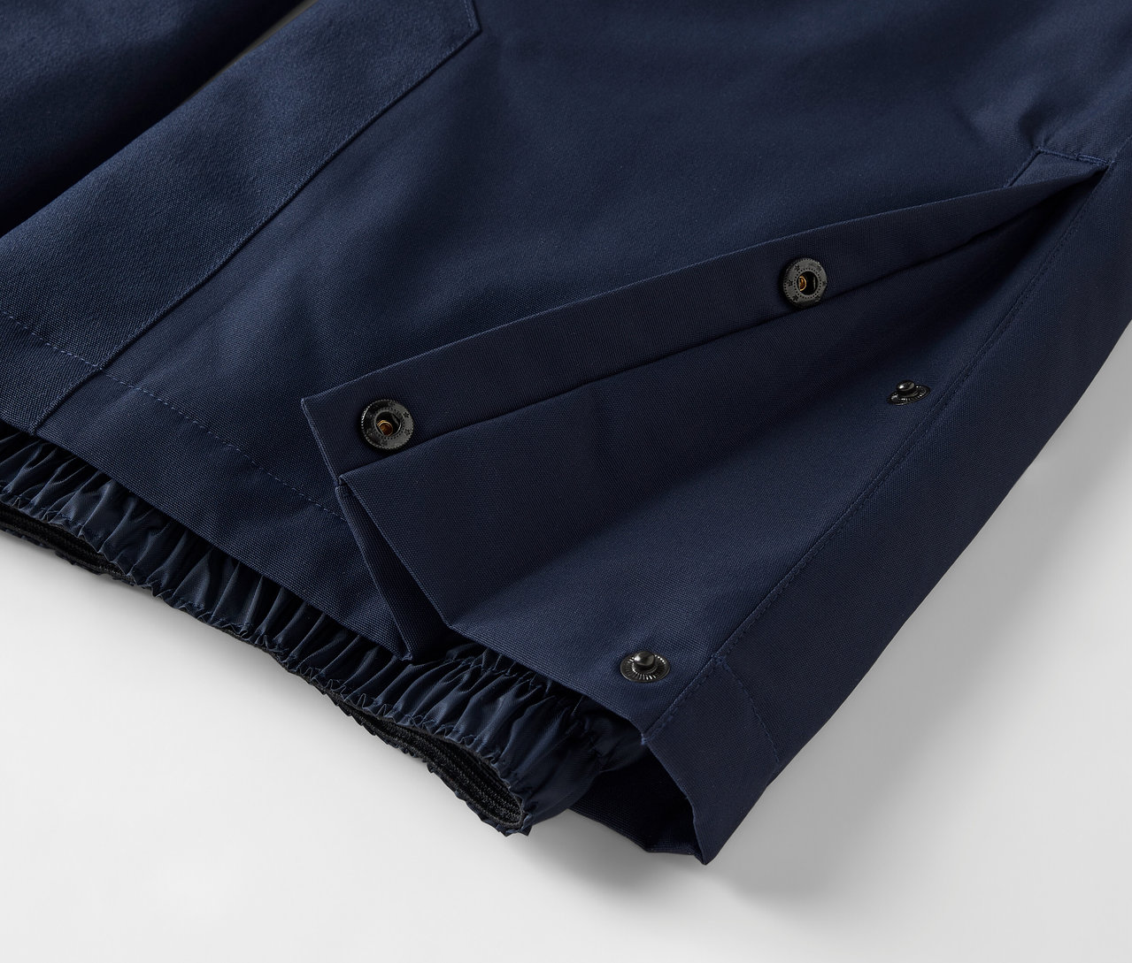 Szczegół niebieskich spodni z zapięciem na zatrzaski i elastycznym obszyciem.