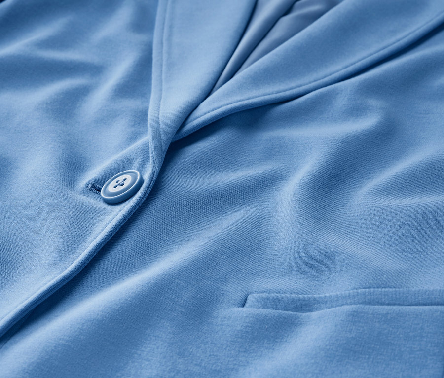 Szczegół jasnoniebieskiej marynarki z dżerseju z guzikiem i kieszenią.