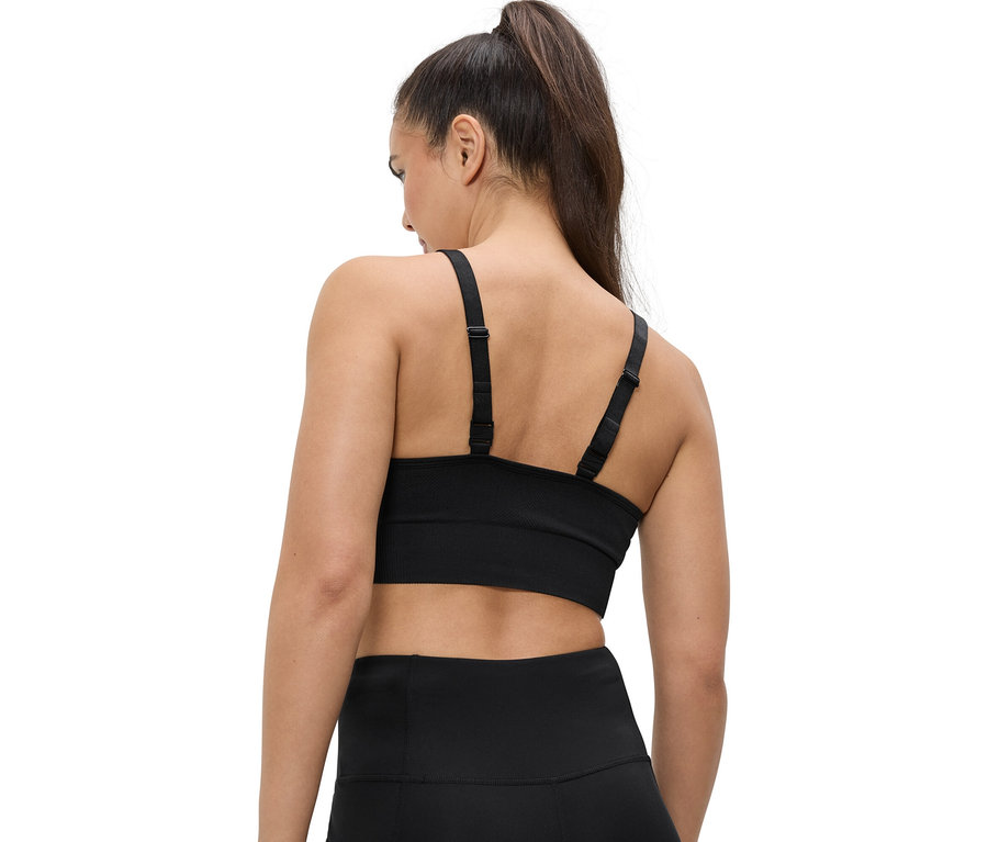 Widok z tyłu kobiety z kucykiem, ubranej w czarny biustonosz sportowy i legginsy.