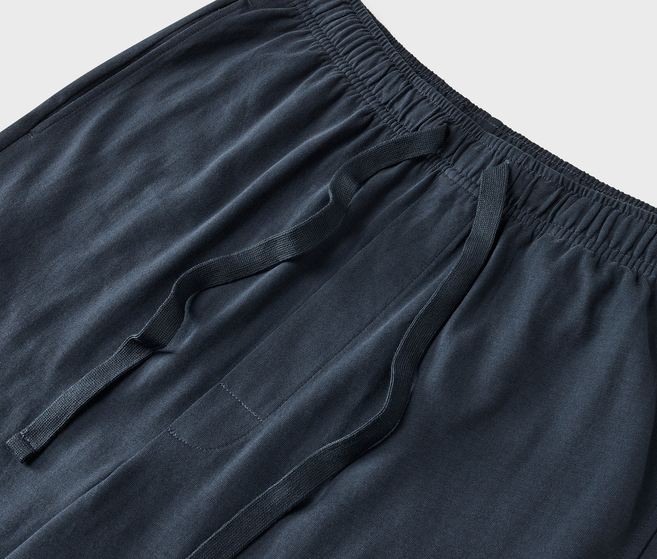 Zbliżenie na granatowe spodnie dresowe ze sznurkiem w pasie.