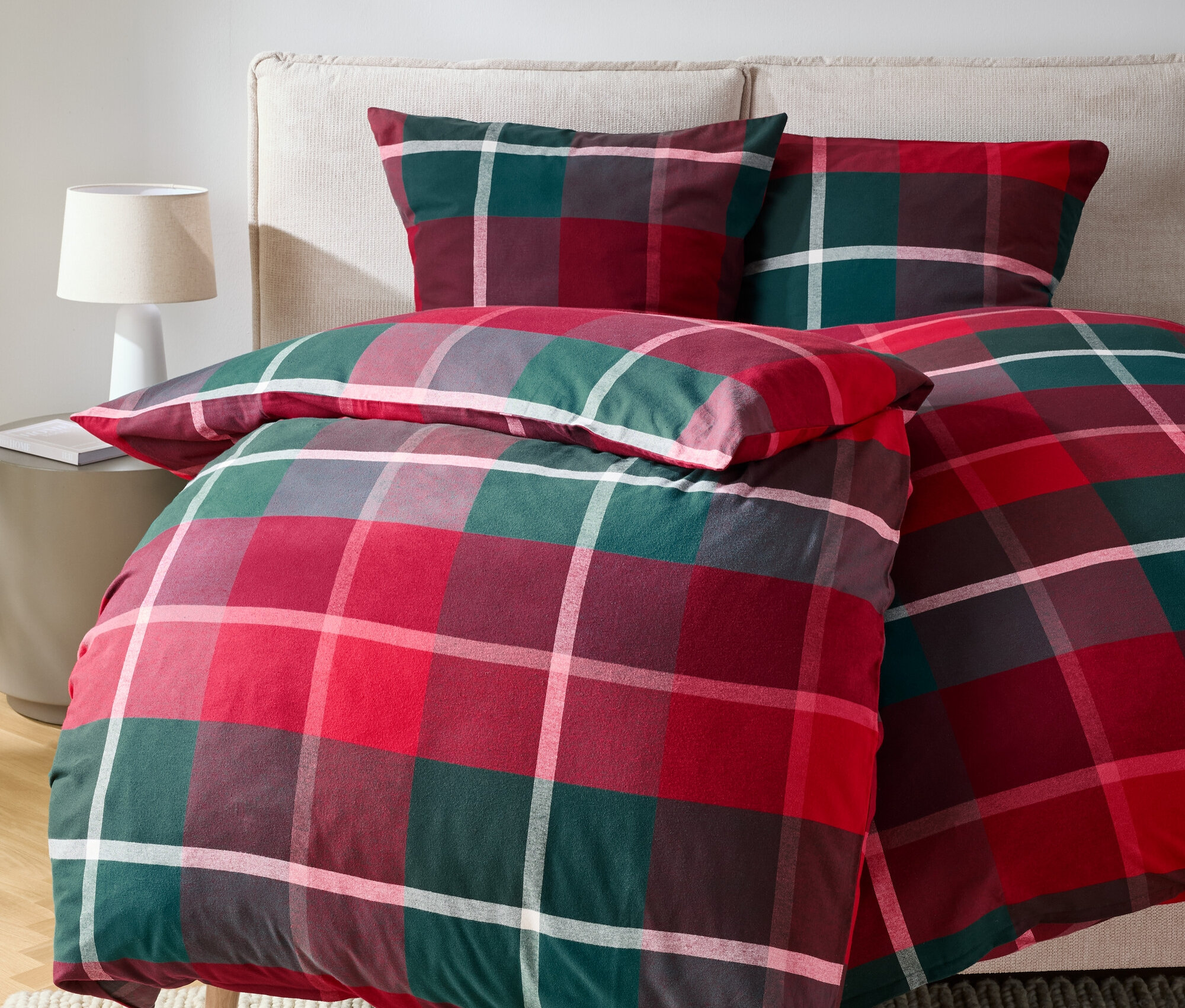 Czerwono-zielona pościel w kratę na łóżku z poduszkami.