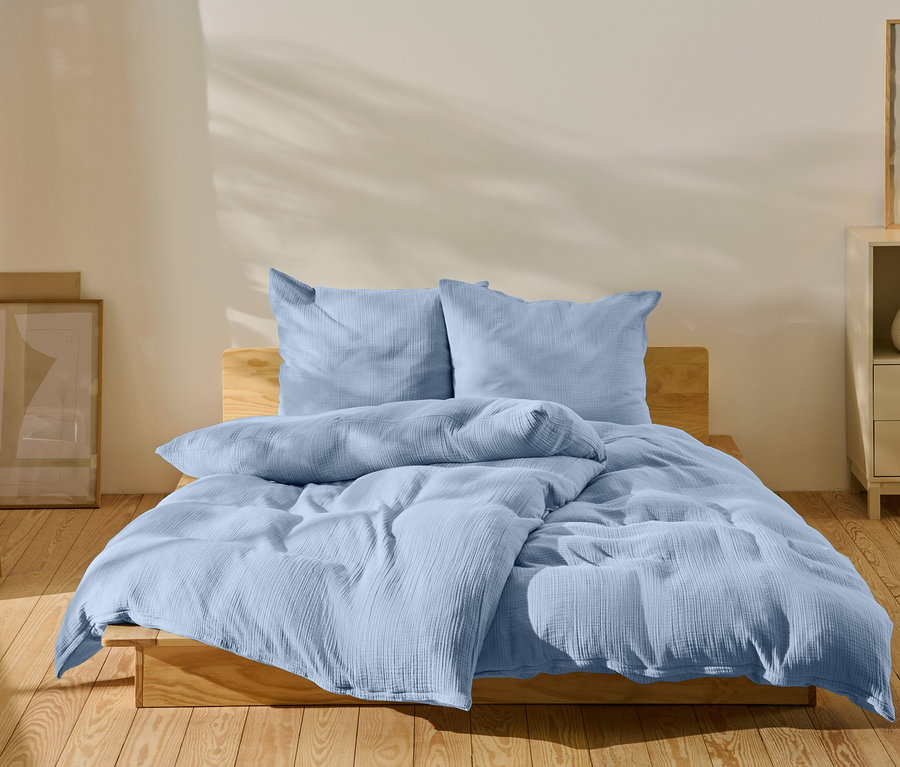 Jasnoniebieska pościel na łóżku w sypialni.