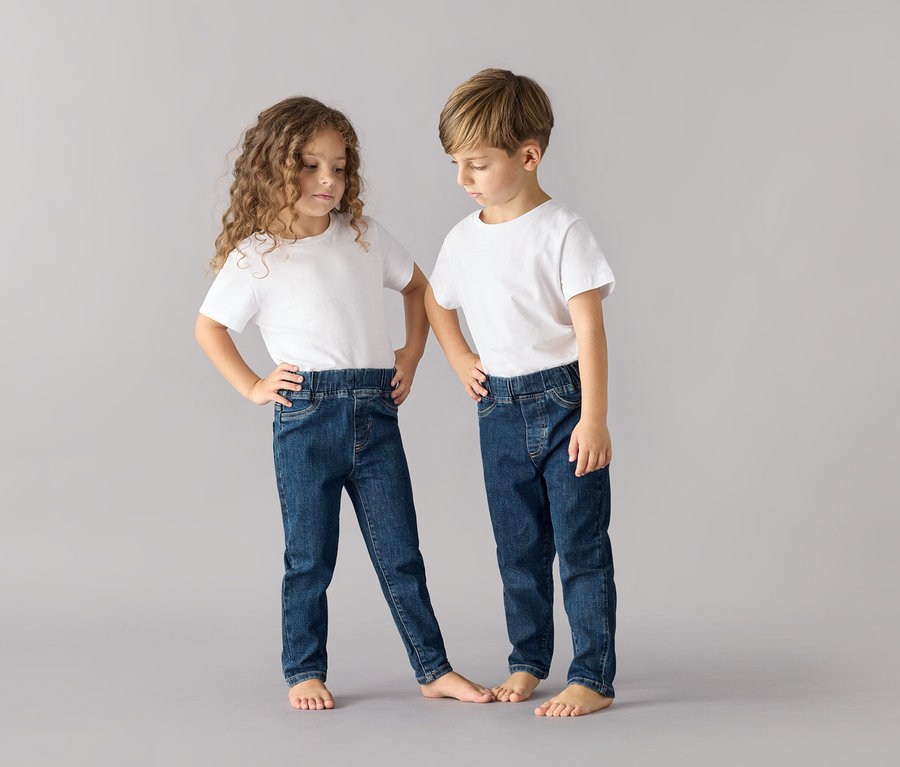 Dwoje dzieci pozuje w białych podkoszulkach i granatowych spodniach na gumce – fason „Luca”.