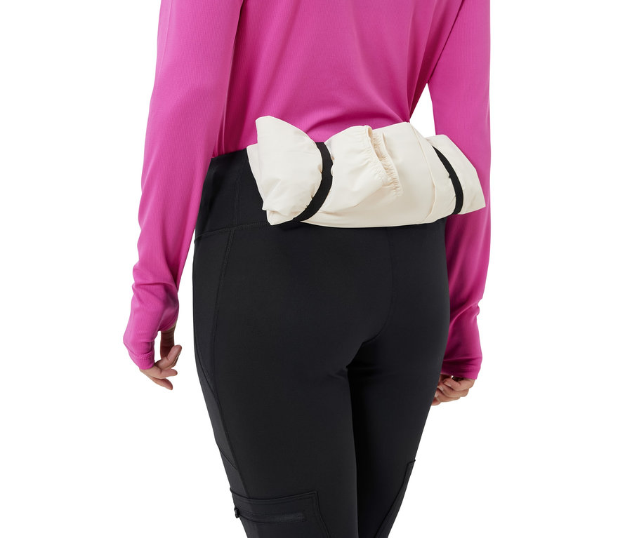 Kobieta ma na sobie czarne legginsy outdoorowe i kremową kurtkę wokół talii.