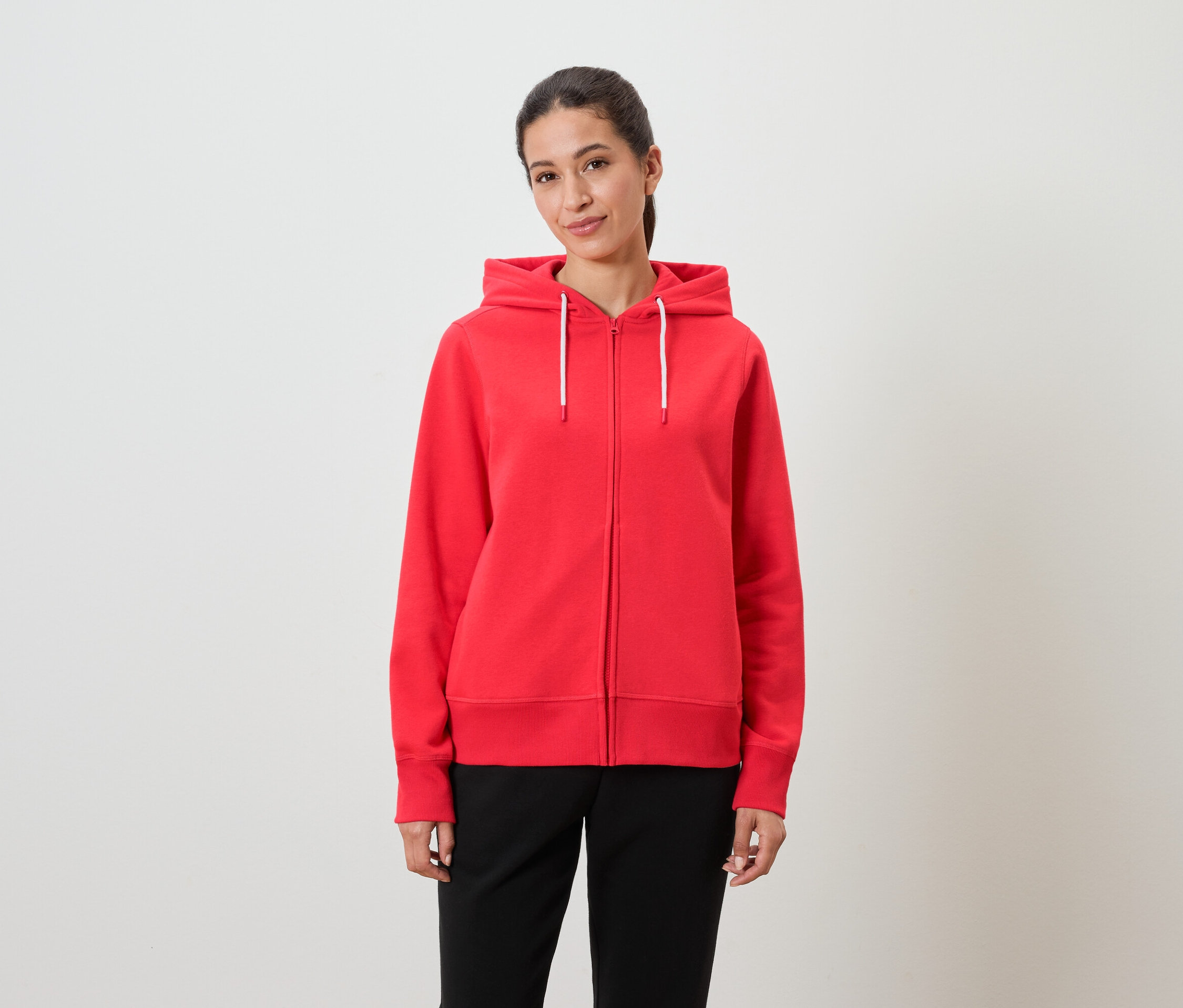Kobieta ma na sobie czerwoną bluzę z kapturem i czarne spodnie.
