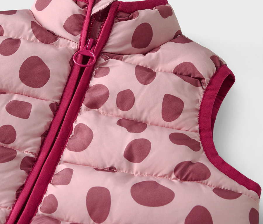 Zbliżenie na różową pikowaną kamizelkę w bordowe kropki z zamkiem błyskawicznym.