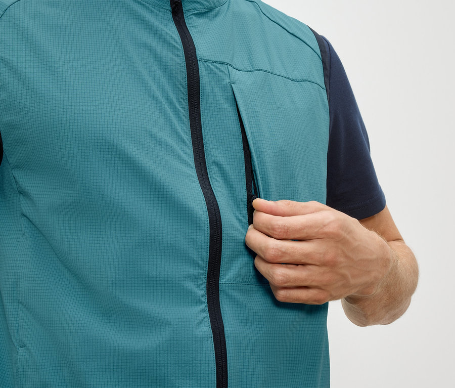 Mężczyzna otwiera kieszeń na zamek błyskawiczny petrolwowej kamizelki.