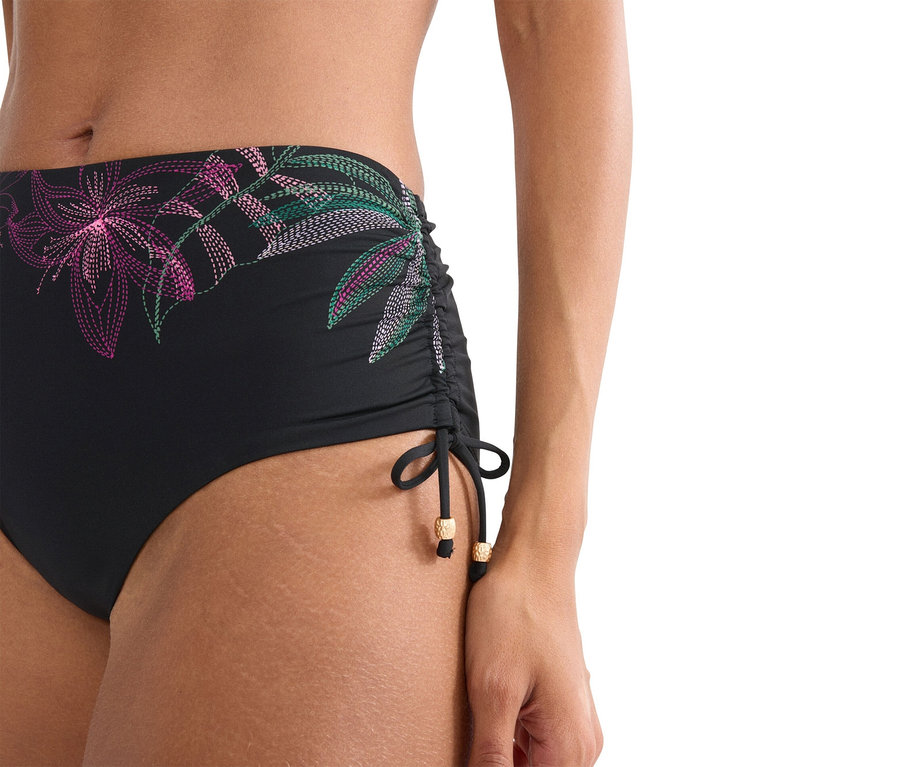 Zbliżenie kobiety w czarnych majtkach od bikini z kwiatowym wzorem.
