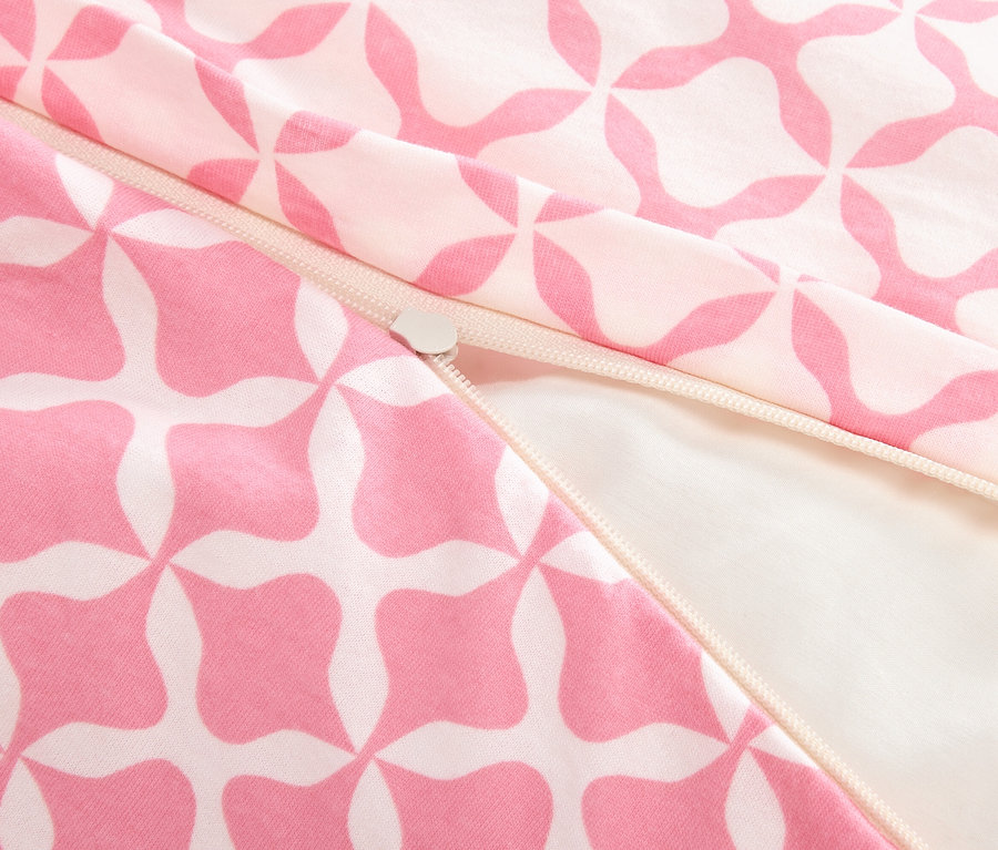 Zbliżenie na częściowo otwarty zamek błyskawiczny na różowo-białej tkaninie.