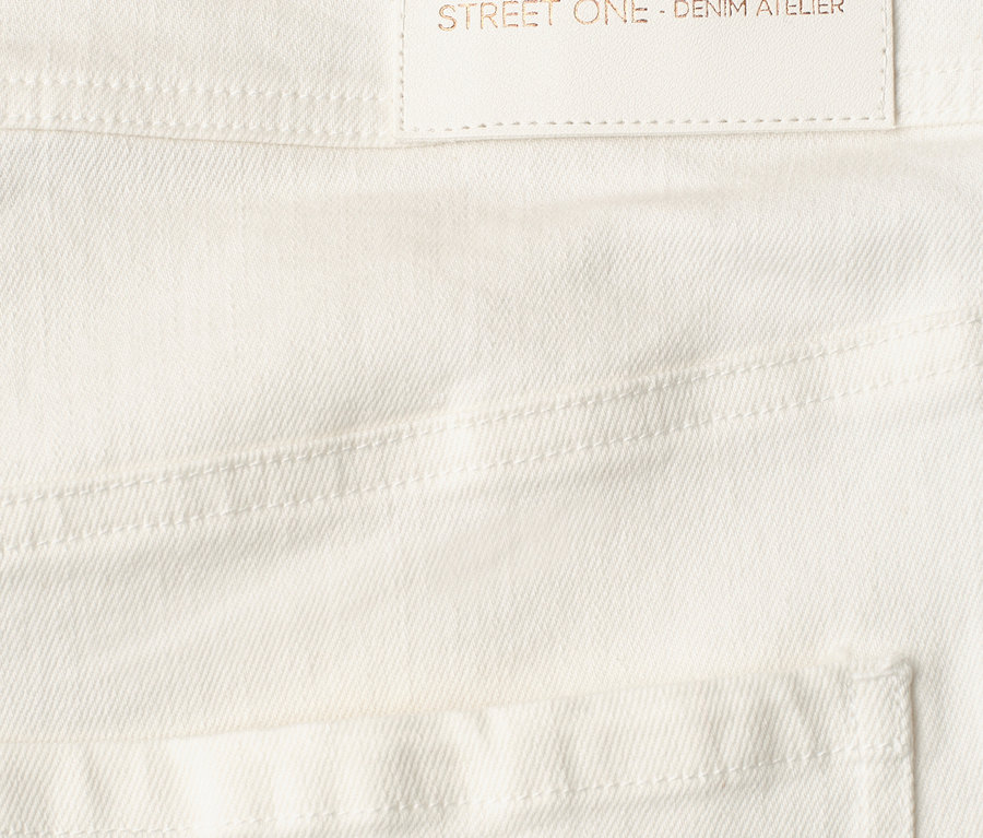 Zbliżenie na białe Street One Jeans z jasną metką z napisem 'designed with passion STREET ONE - DENIM ATELIER'.