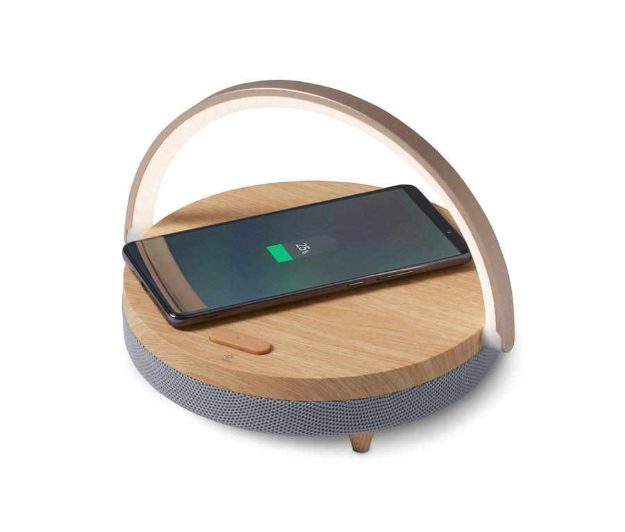 Telefon komórkowy ładuje się na głośniku Bluetooth z bezprzewodową ładowarką i lampką LED.