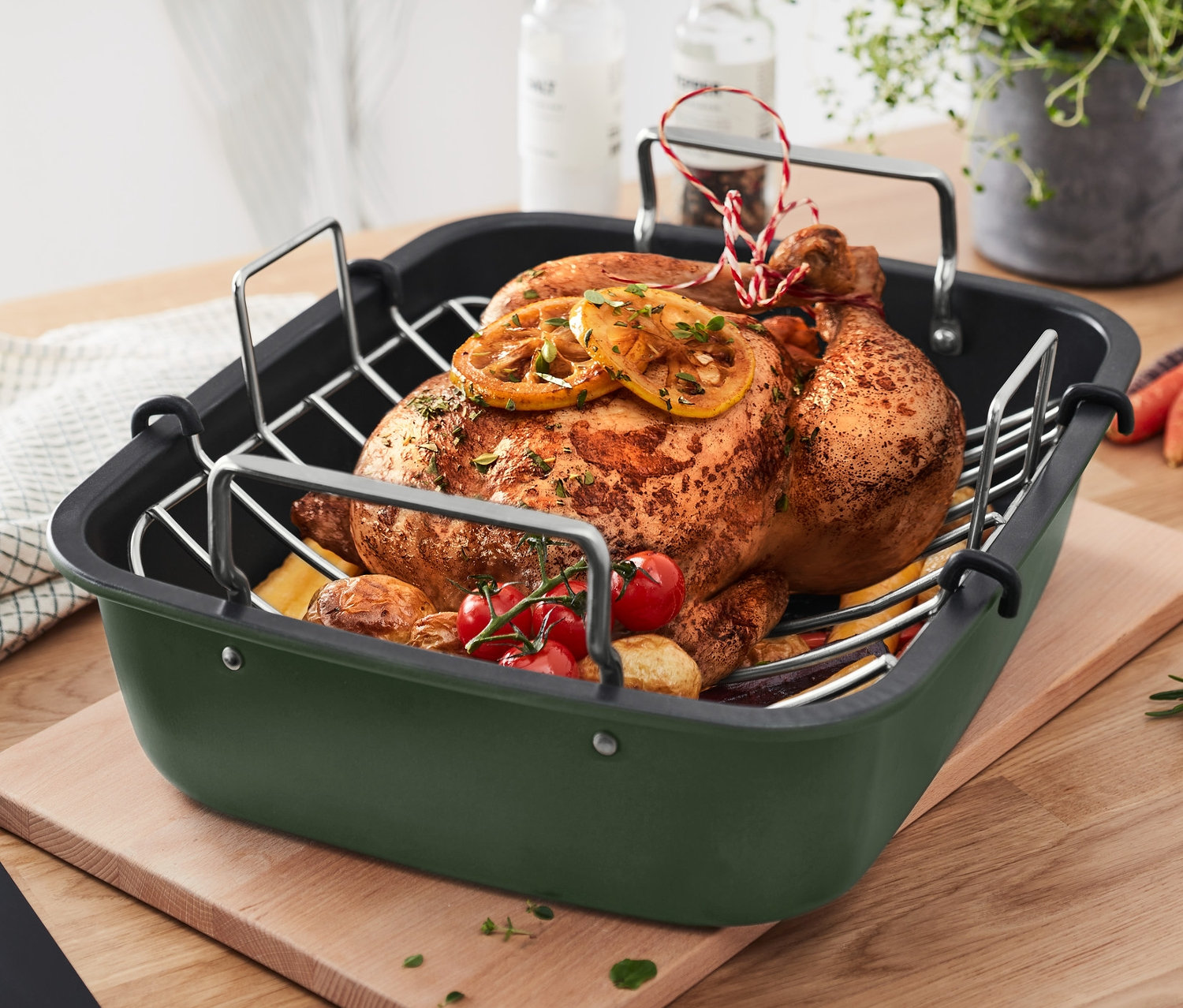 Pieczony kurczak z cytryną i warzywami w brytfannie XL ze stali nierdzewnej z rusztem na drewnianej desce do krojenia.