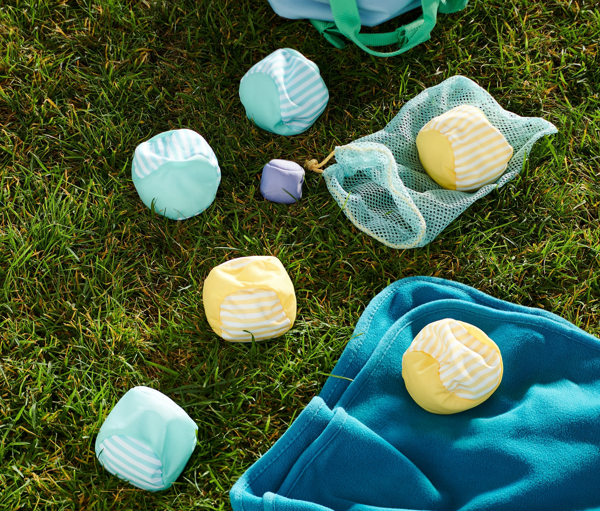 Na trawie leżą gra boccia soft, niebieska torba i niebieski koc.