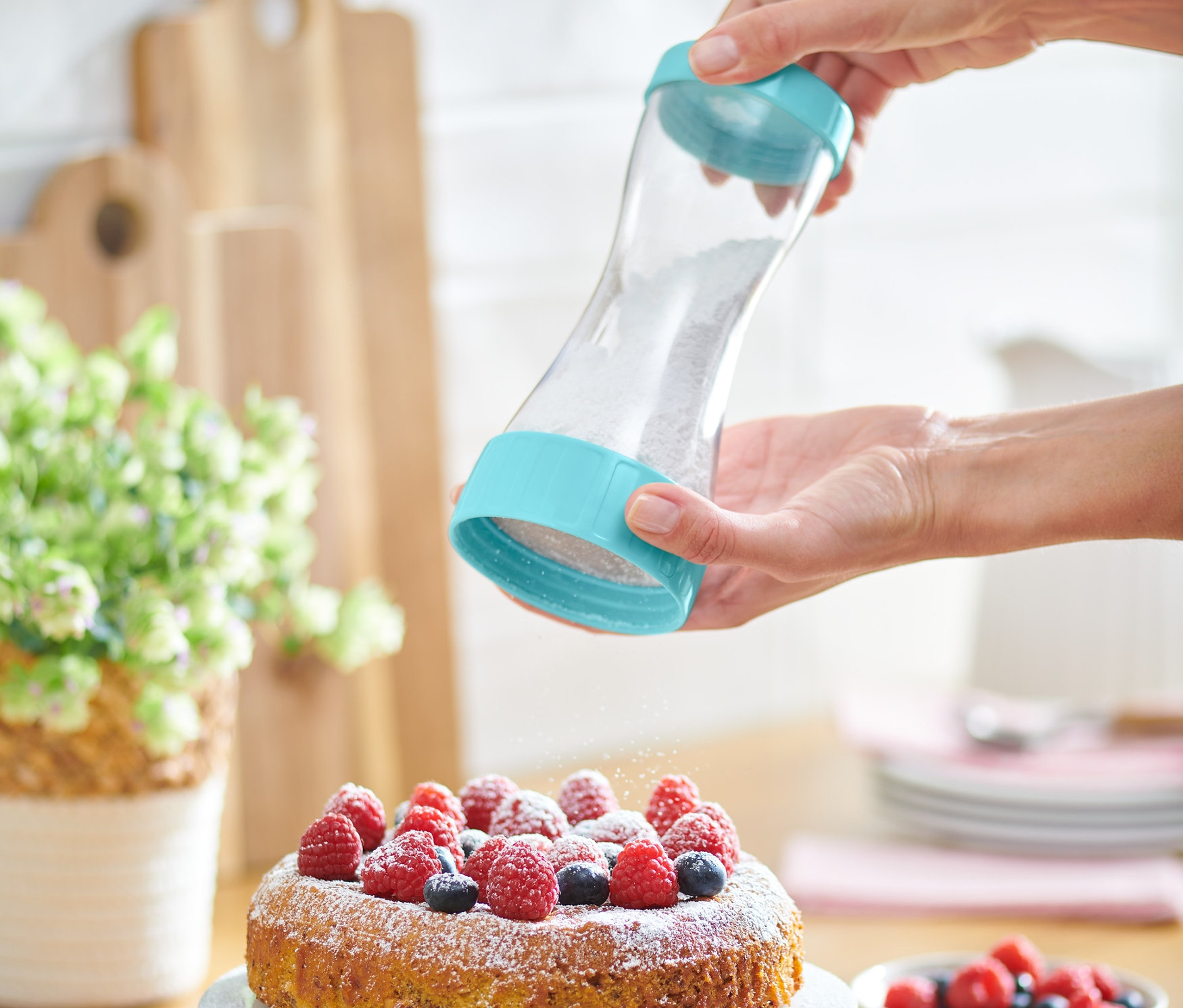 Kobieta posypuje ciasto cukrem pudrem za pomocą dozownika do cukru pudru.