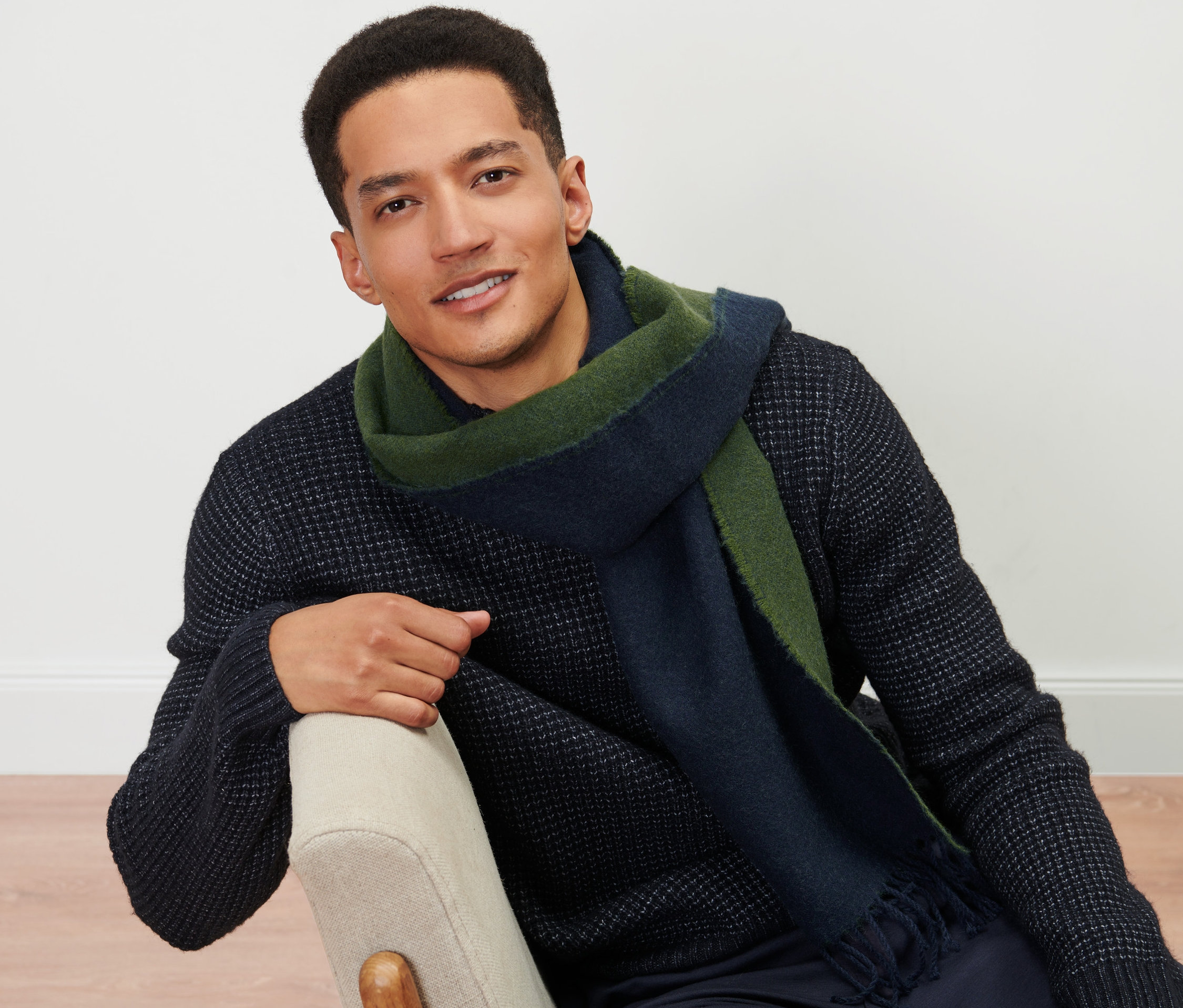 Mężczyzna siedzi na krześle i ma na sobie tkany szalik.