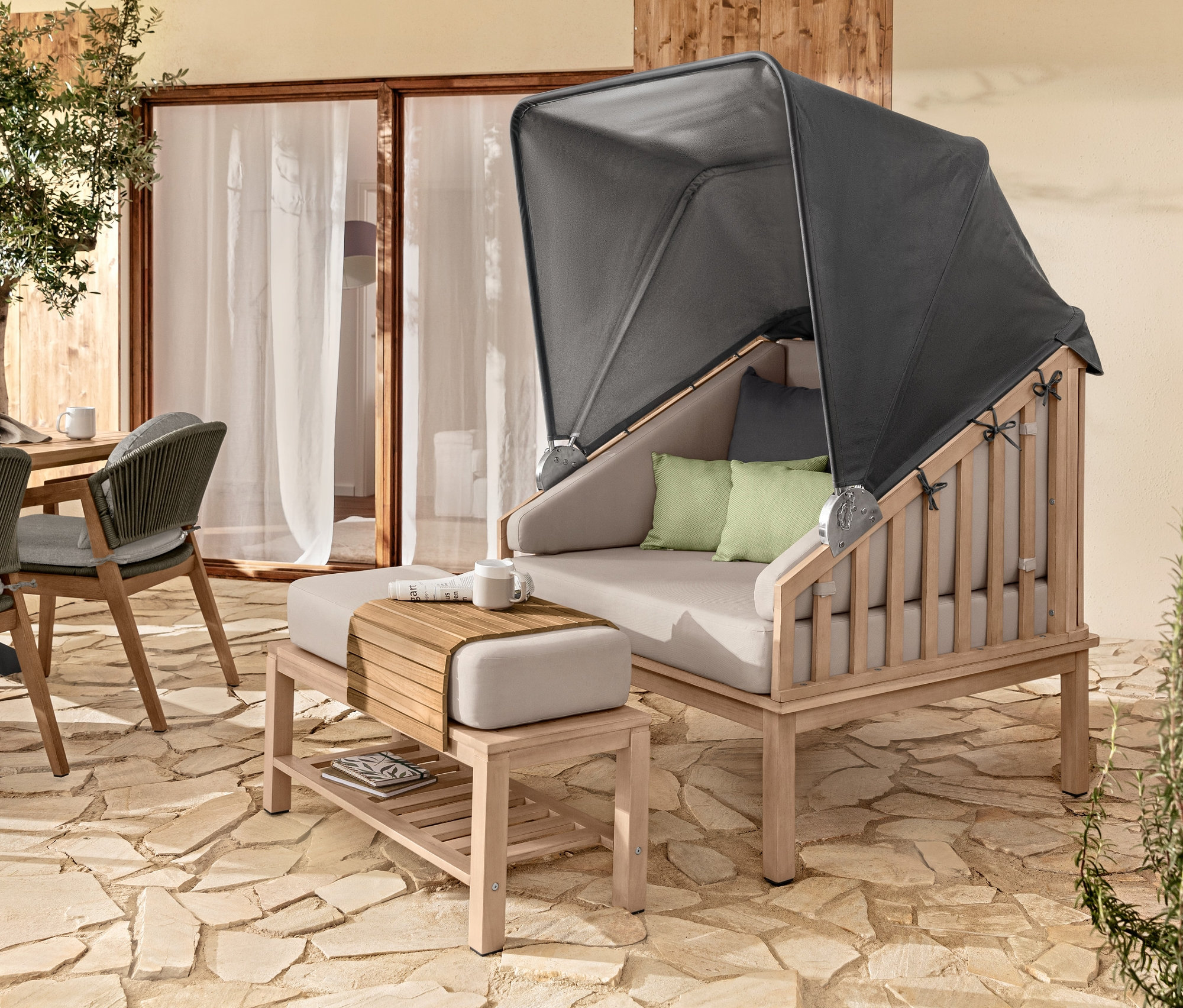 Aranżacja na zewnątrz z koszem plażowym premium z daszkiem przeciwsłonecznym, elastyczną tacą na sofę z drewna tekowego i 2 poduszkami outdoorowymi.