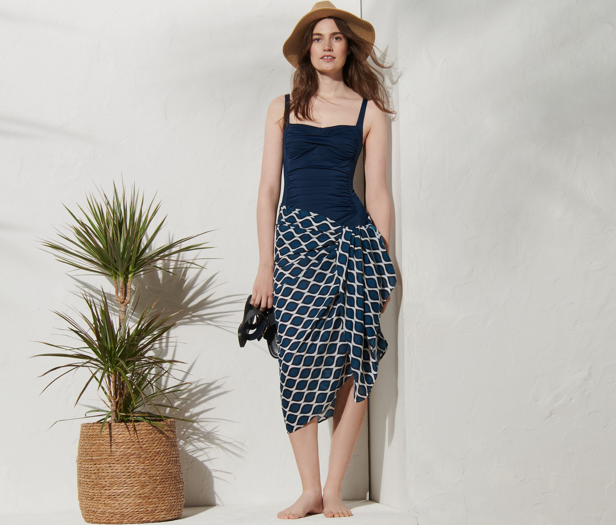 Kobieta w niebieskim kostiumie kąpielowym i wzorzystej chuście wielofunkcyjnej.