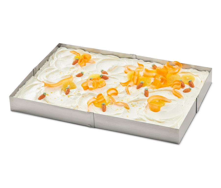 Ciasto ozdobione skórką pomarańczową i marchewką w ramce do pieczenia ze stali nierdzewnej.