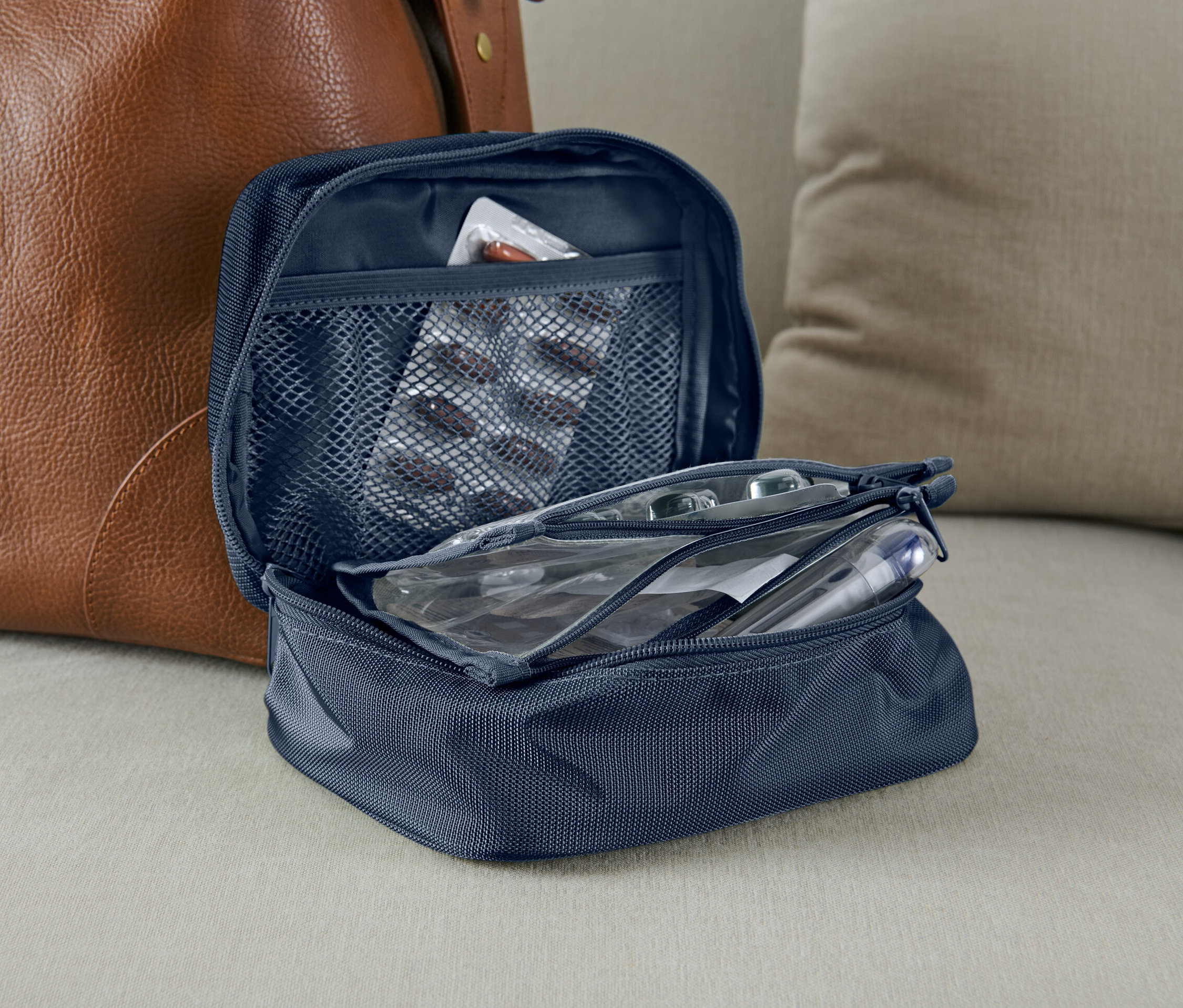 Otwarta niebieska torba na leki obok brązowej skórzanej torby.