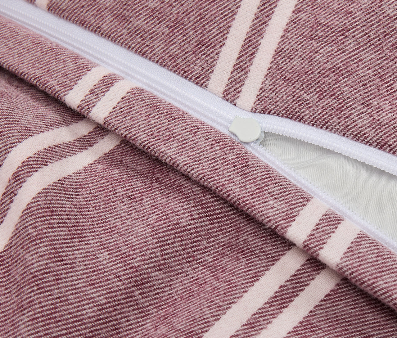 Szczegół fioletowo-białej poszewki na poduszkę w paski z zamkiem błyskawicznym.