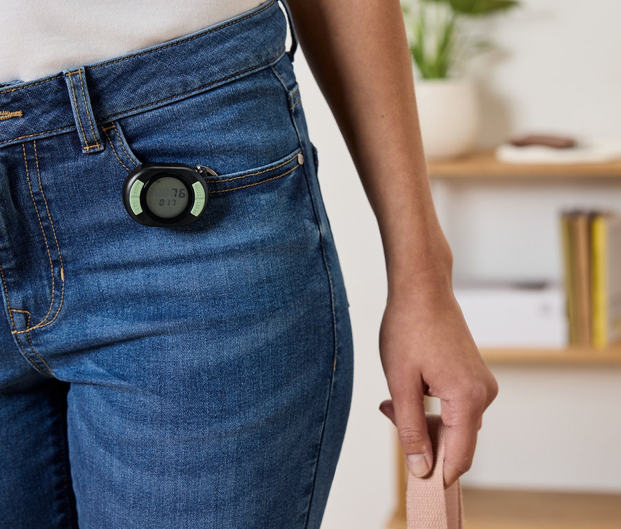 Czarny krokomierz przymocowany do przedniej kieszeni niebieskich dżinsów.