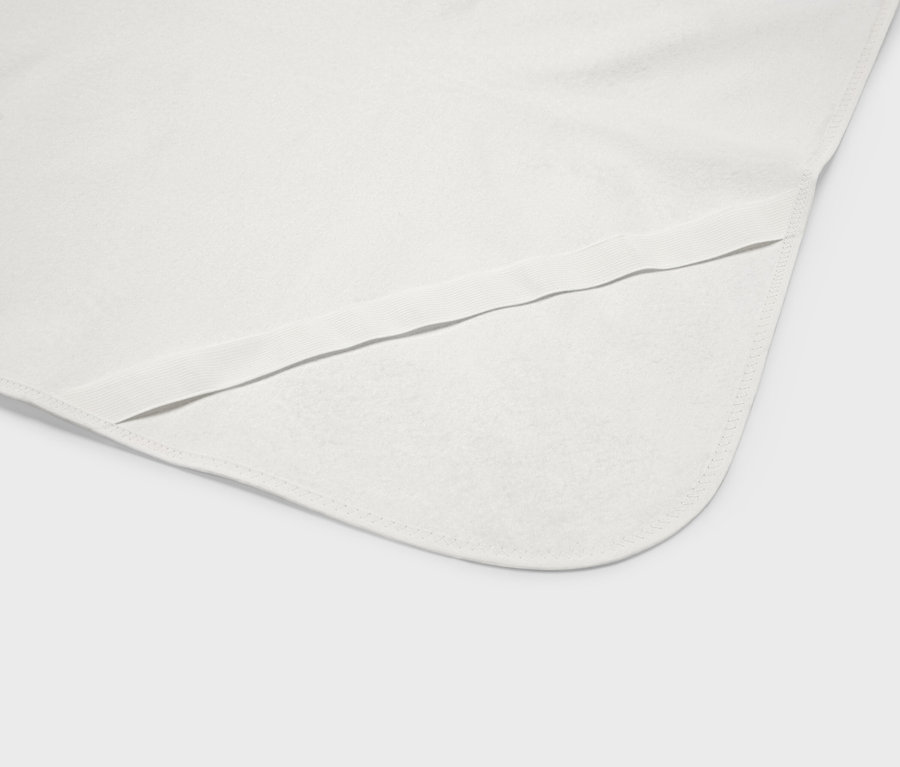 Zbliżenie białego koca dla niemowląt z zaokrąglonymi rogami i elastycznym obszyciem.