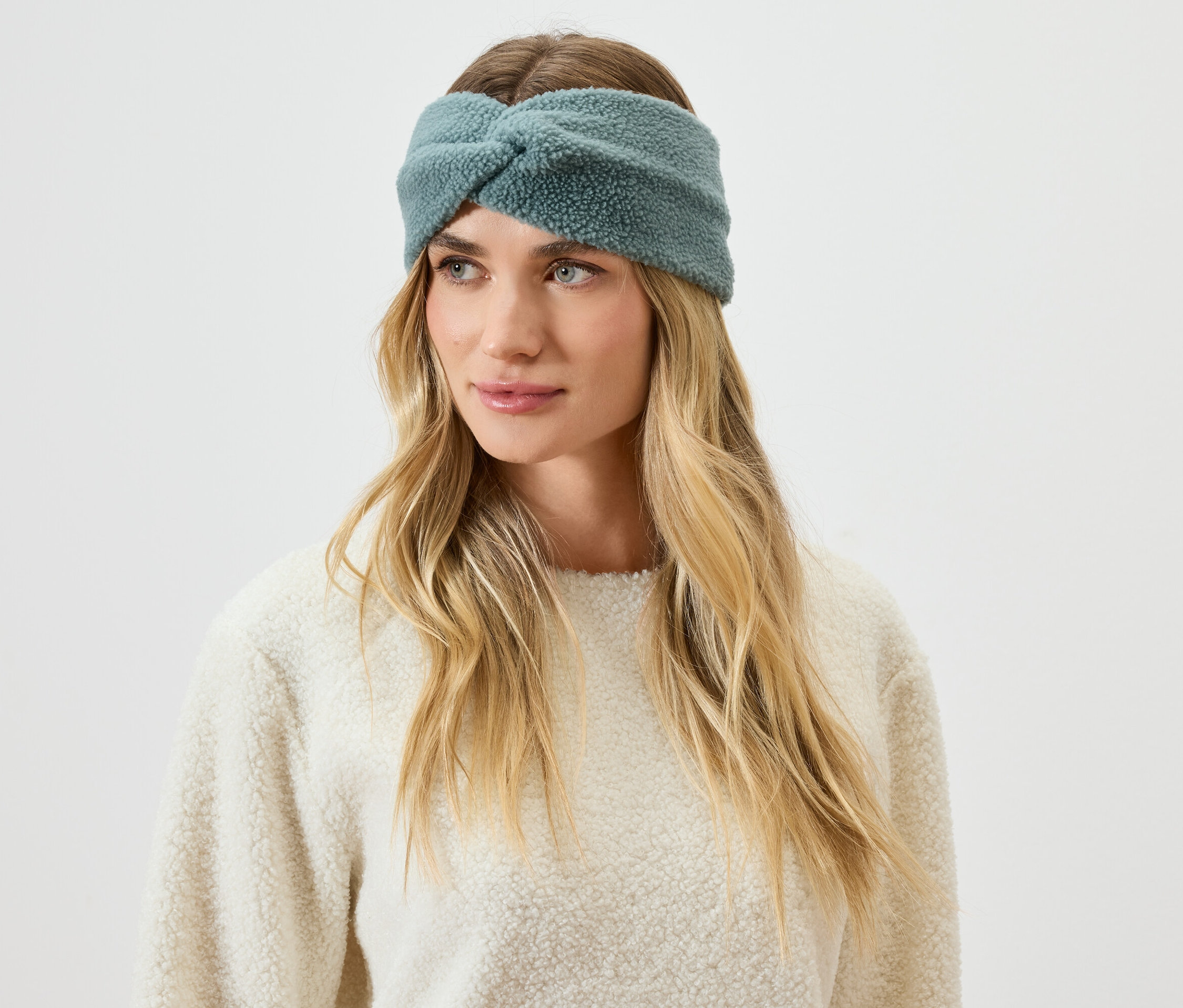 Portret kobiety o blond włosach, ubranej w niebiesko-zieloną, włochatą opaskę na głowę.