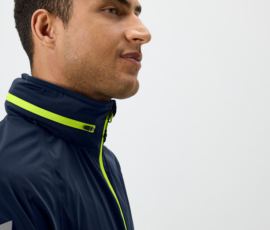 Profil mężczyzny w granatowej kurtce z żółtymi detalami.