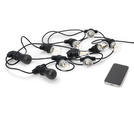 Czarny łańcuch świetlny LED z dwoma głośnikami Bluetooth® do użytku na zewnątrz leży obok telefonu komórkowego na białym tle.