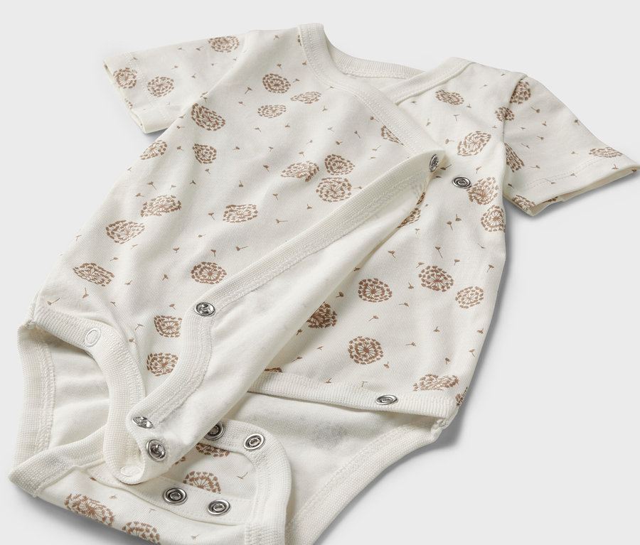 Zbliżenie na białe body niemowlęce z krótkim rękawem w nadruk z dmuchawców, 5 sztuk.