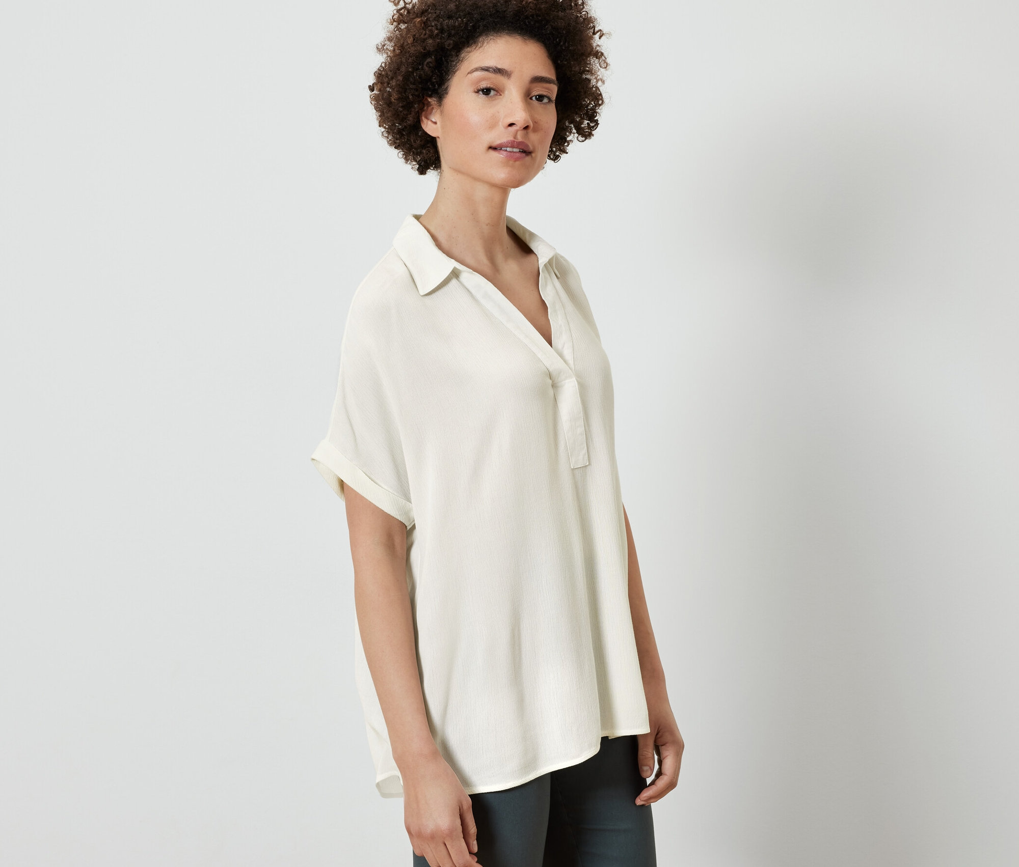Kobieta pozuje w kremowej bluzce.