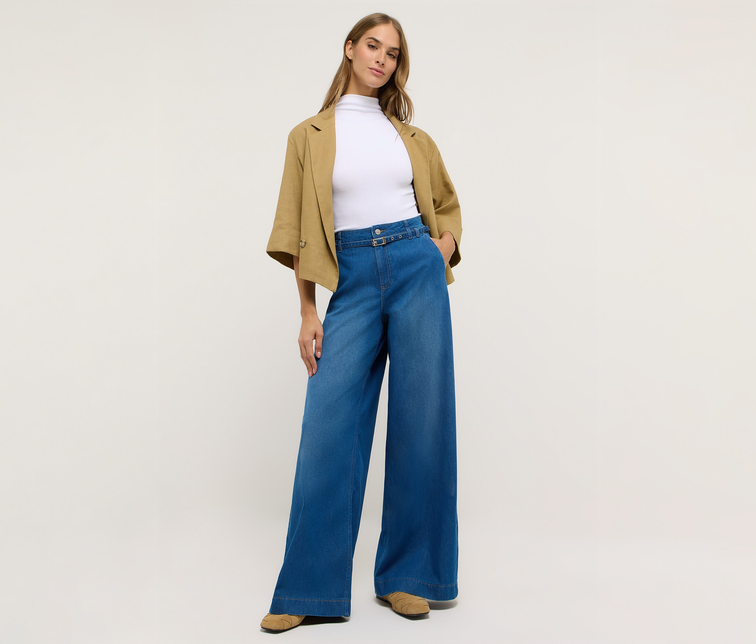 Kobieta w dżinsach Angels „Liva” Sleek Wide Leg, białym topie i kurtce.