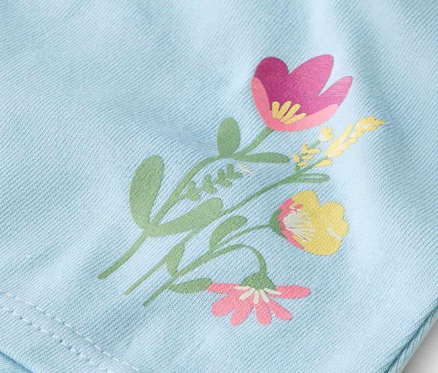 Zbliżenie na jasnoniebieski materiał z nadrukowanym wzorem kwiatowym.