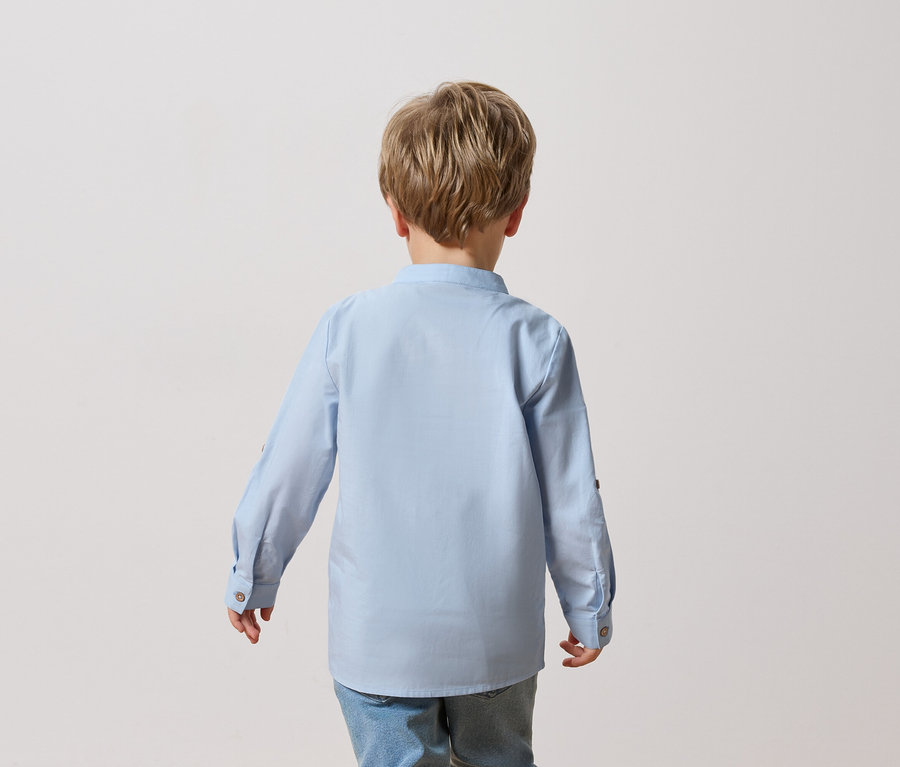 Widok z tyłu dziecka o blond włosach w jasnoniebieskiej koszuli i dżinsach.