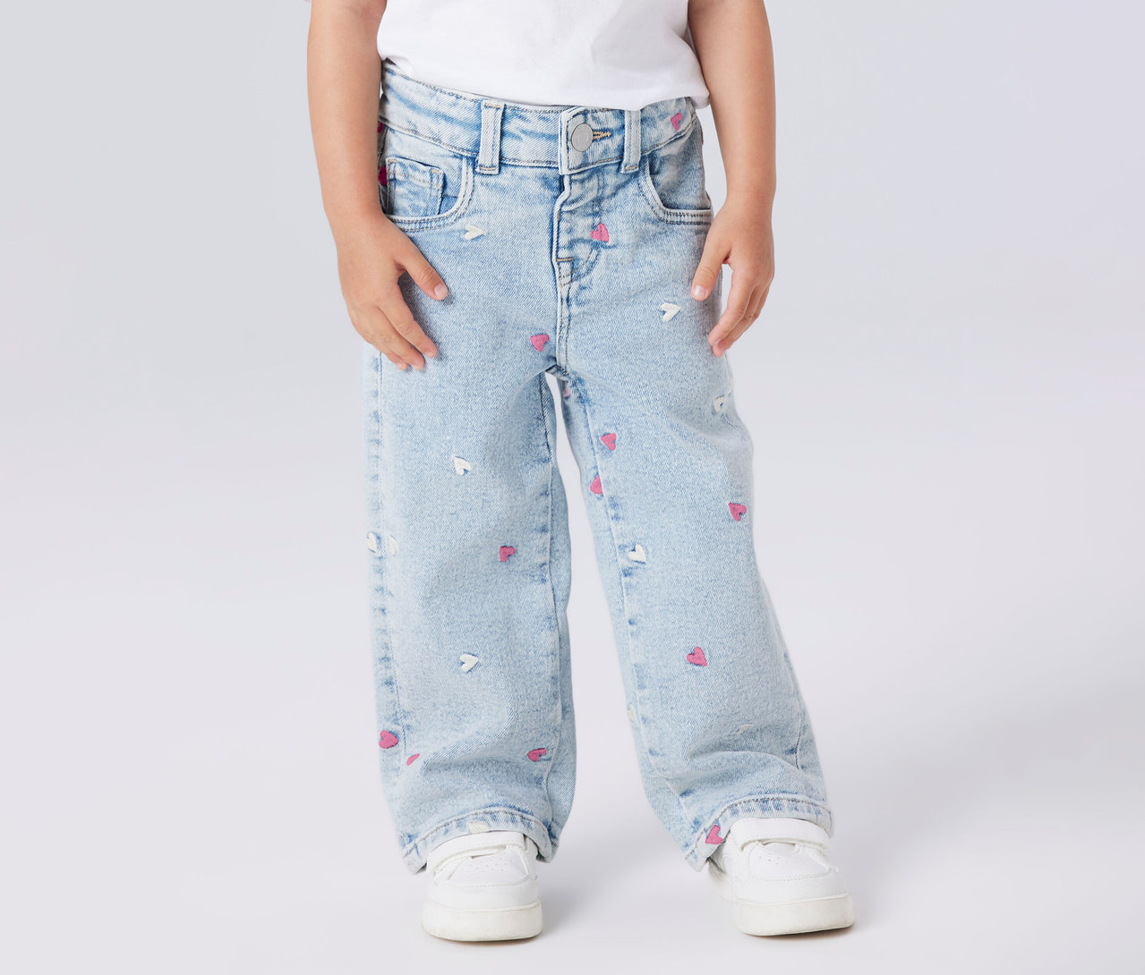 Dziecko nosi jeansy Wide Leg NAME IT z motywem serca i białe buty.
