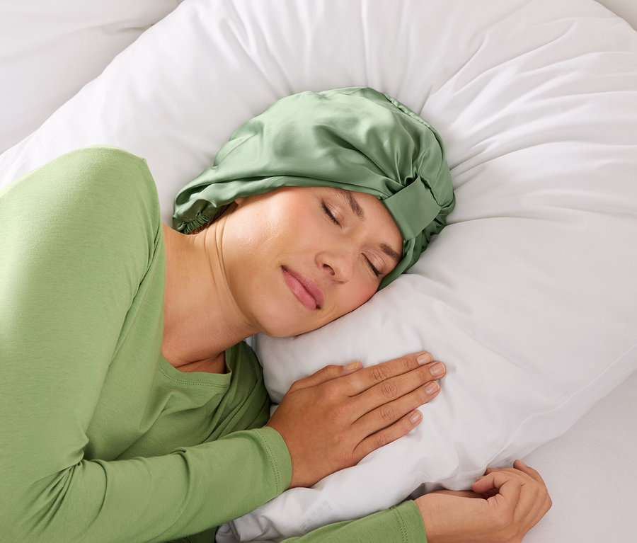 Kobieta śpi w zielonej opasce na włosy na białej poduszce.