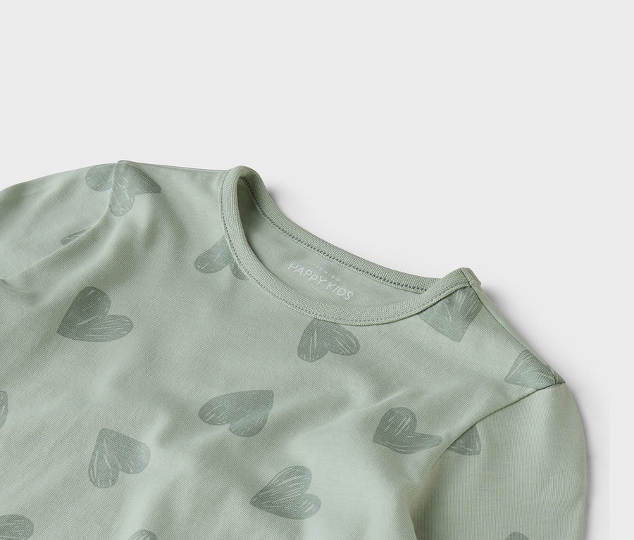 Zbliżenie jasnozielonej bluzki z długim rękawem z szarym wzorem w serca.