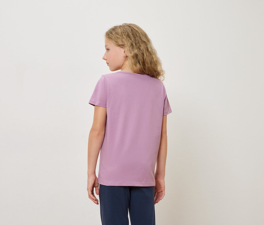 Widok z tyłu blondynki w fioletowej koszulce i niebieskich spodniach na białym tle.